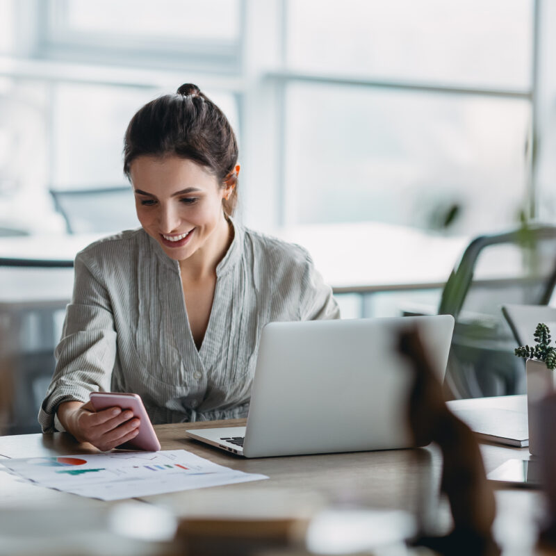 Photo d'une femme regardant son téléphone à son bureau