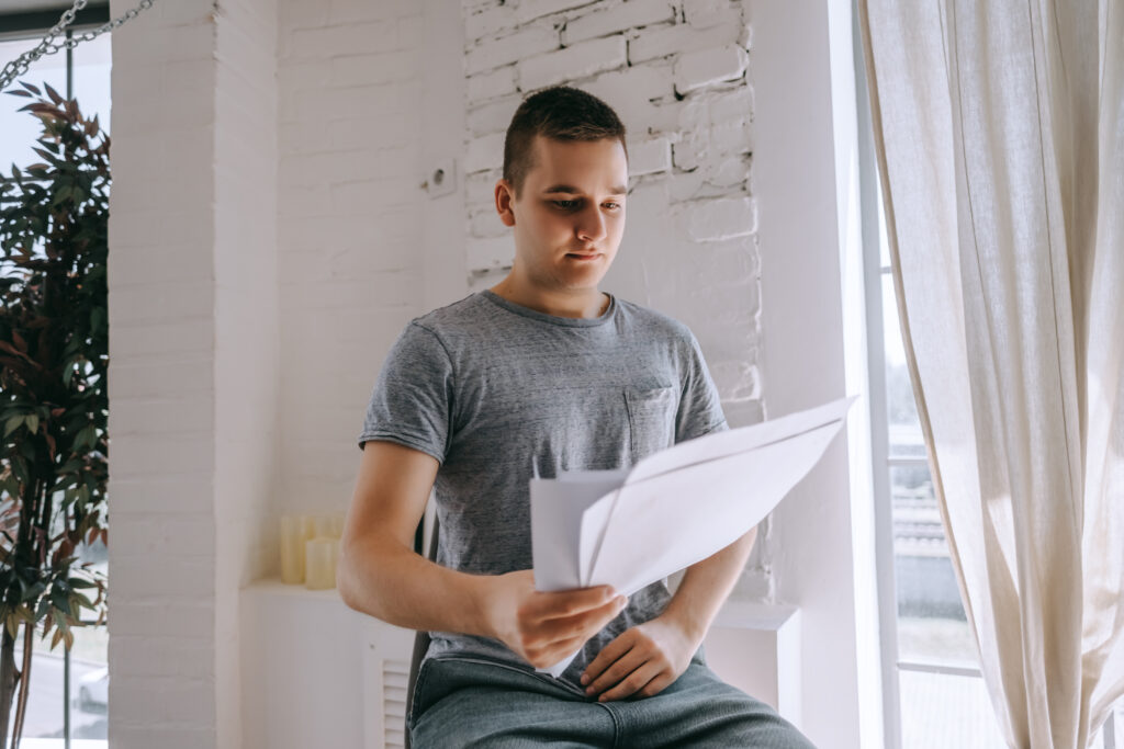 Homme sur une chaise tenant des documents papiers à la main