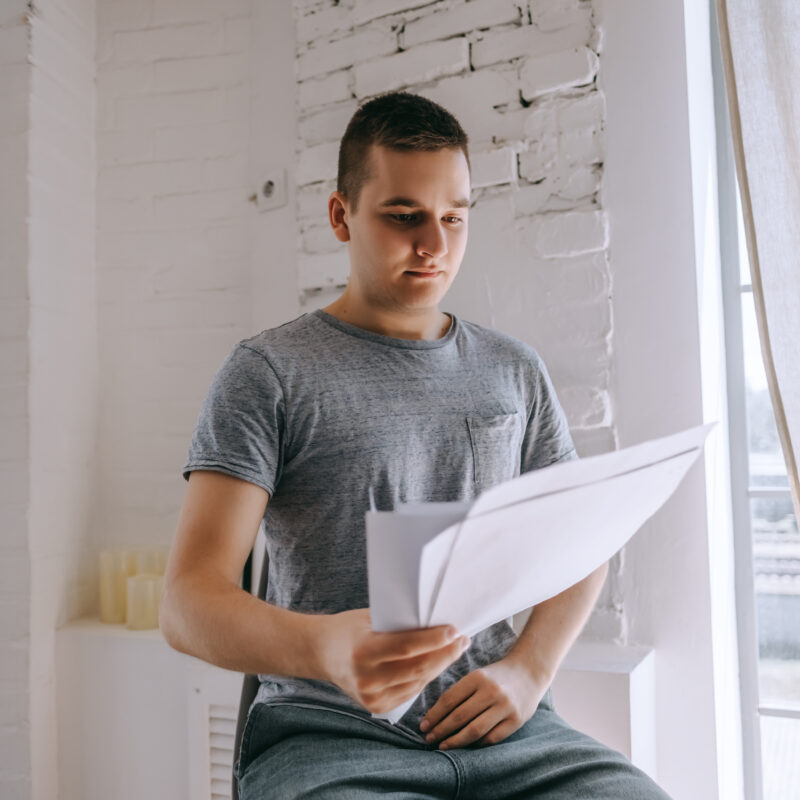 Homme sur une chaise tenant des documents papiers à la main