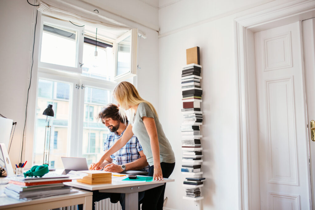 Deux personnes dans un bureau, une debout et une assise, en train de travailler