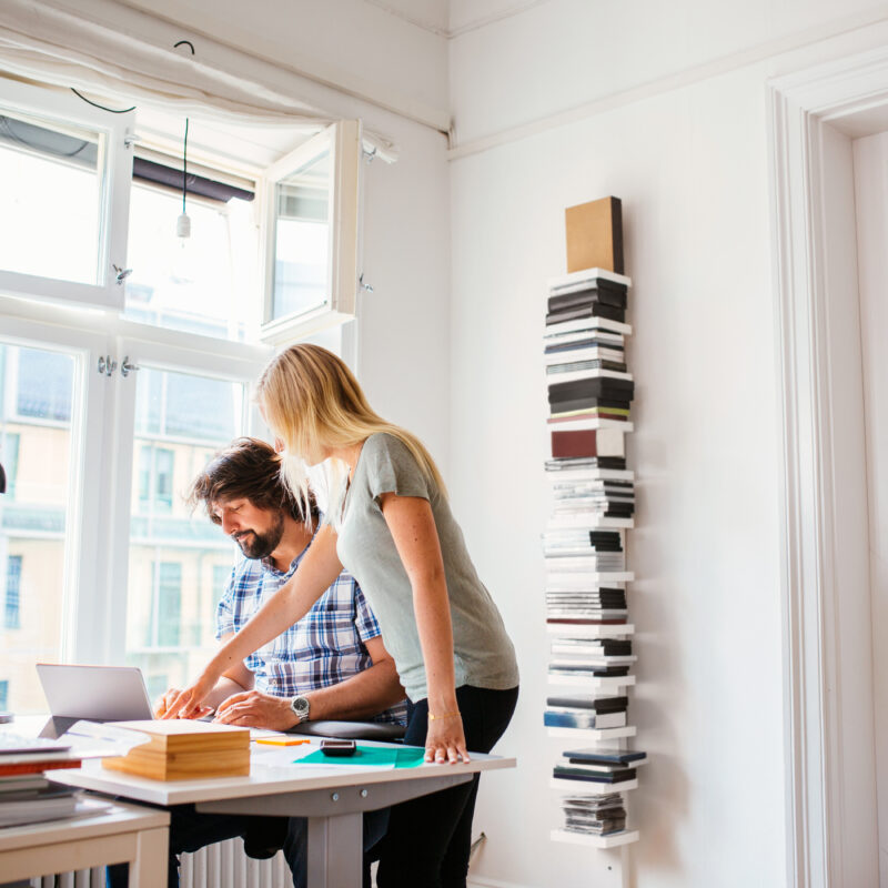 Deux personnes dans un bureau, une debout et une assise, en train de travailler