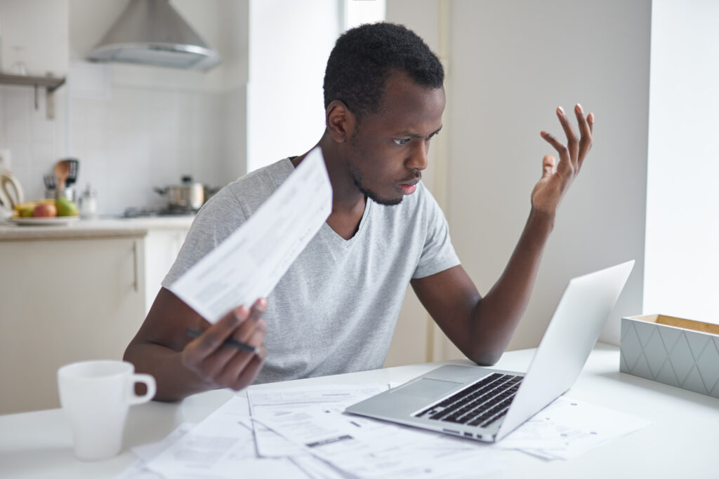 Un homme devant un ordinateur portable avec des papiers à la main