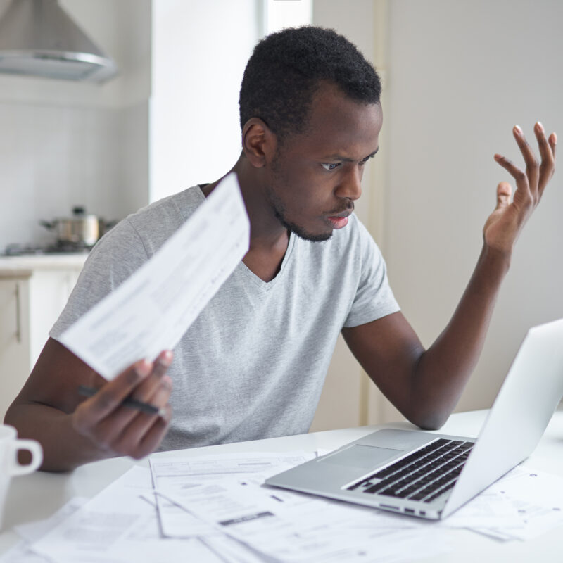 Un homme devant un ordinateur portable avec des papiers à la main