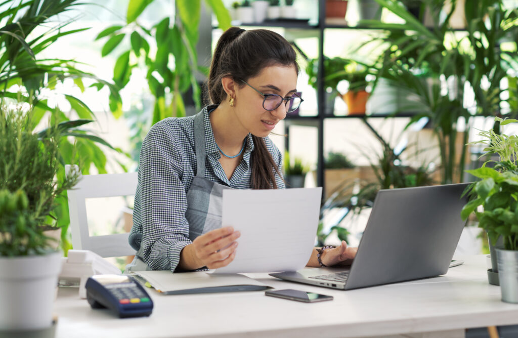 Femme fleuriste gérant sa comptabilité, devant son ordinateur portable dans sa boutique